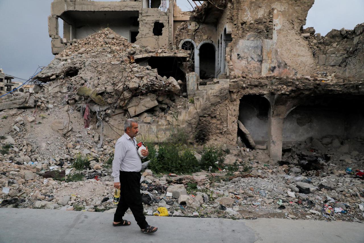 A man walks back to his home after shopping from a wholesale market ahead of the holy fasting month of Ramadan, amid rising commodity prices in Mosul