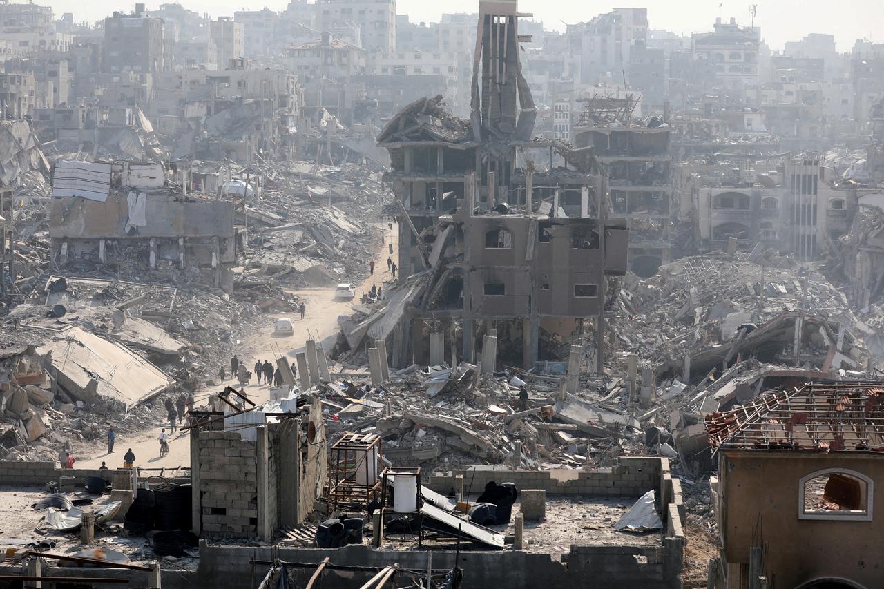 FILE PHOTO: People walk past the rubble of destroyed buildings, in Jabalia in the northern Gaza Strip