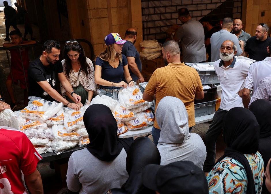 Lebanese volunteers distribute free meals from a local restaurant "Carneo", to the people living in a shelter for displaced families, in Beirut