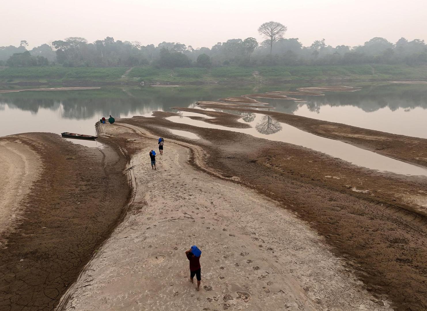 A drone view shows river dwellers carrying water gallons on the sandbanks of the Madeira river to bring to the isolated region of Paraizinho community, during the worst drought of the river in history, Humaita, Amazonas state, Brazil September 8, 2024. REUTERS/Bruno Kelly Photo: BRUNO KELLY/REUTERS