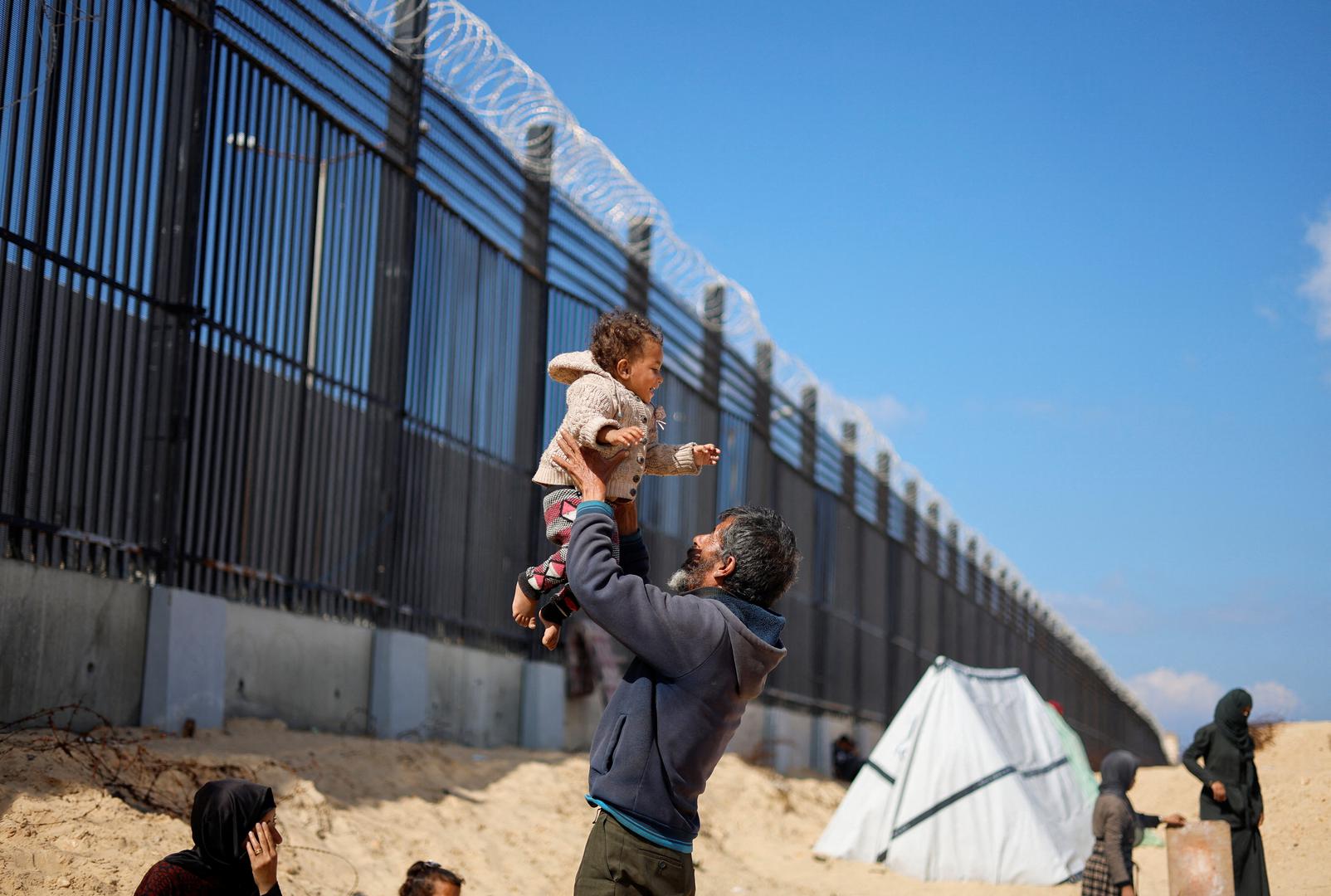 Displaced Palestinian man Naser Abu Mustafa, who fled his house due to Israeli strikes, holds his granddaughter as he shelters at the border with Egypt, in Rafah in the southern Gaza Strip, February 10, 2024. REUTERS/Mohammed Salem Photo: MOHAMMED SALEM/REUTERS