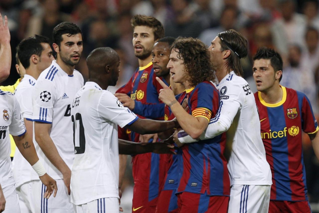 \'Real Madrid\'s players and Lassana Diarra (C) react against Barcelona\'s players and captain Carles Puyol (3rd R) during their Champions League semi-final first leg soccer match at Santiago Bernabeu