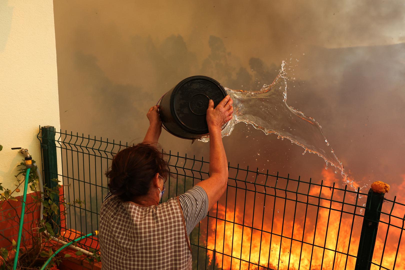 A woman tries to extinguish a wildfire next to her house in Vilarinho, Portugal, September 17, 2024. REUTERS/Pedro Nunes Photo: PEDRO NUNES/REUTERS