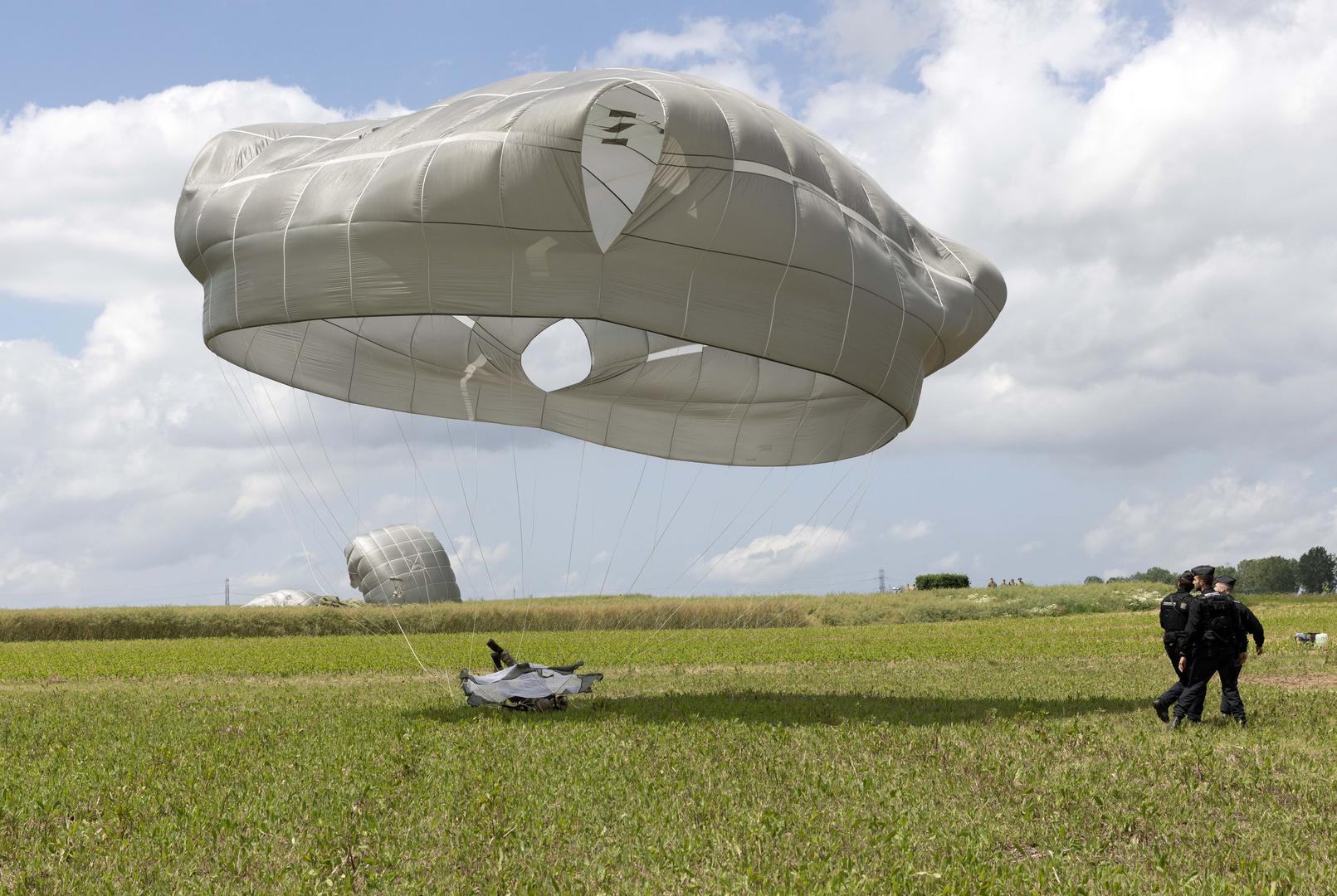 Paratroopers land close to French police during a commemorative jump into fields around the French village of Sanneville in Normandy as part of the 80th anniversary of D-day.  05.06.2024   Material must be credited "The Times/News Licensing" unless otherwise agreed. 100% surcharge if not credited. Online rights need to be cleared separately. Strictly one time use only subject to agreement with News Licensing Photo: Richard Pohle/NEWS SYNDICATION