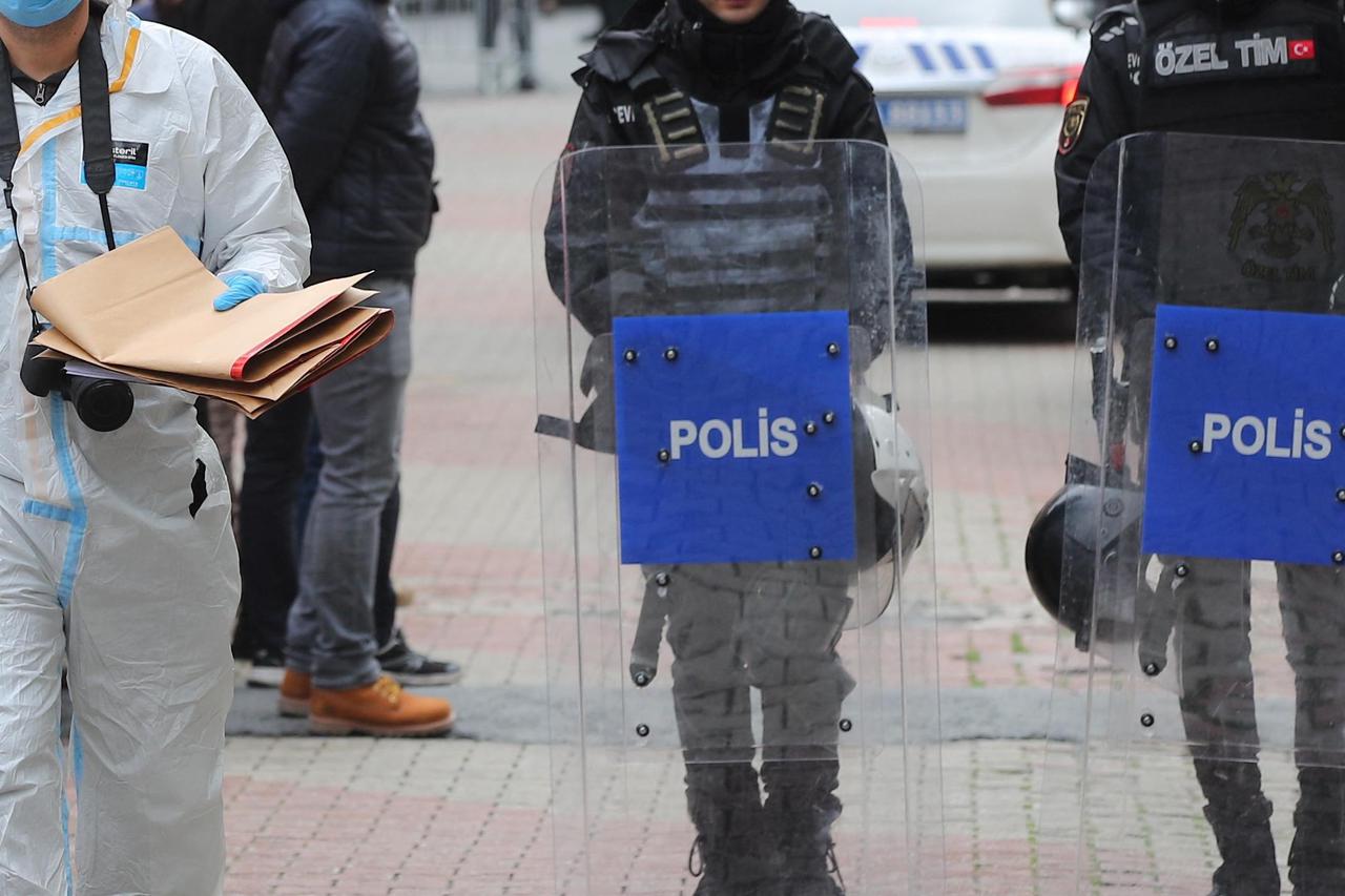 A police forensic expert examines as Turkish police stand guard outside the Santa Maria Catholic Church in Istanbul