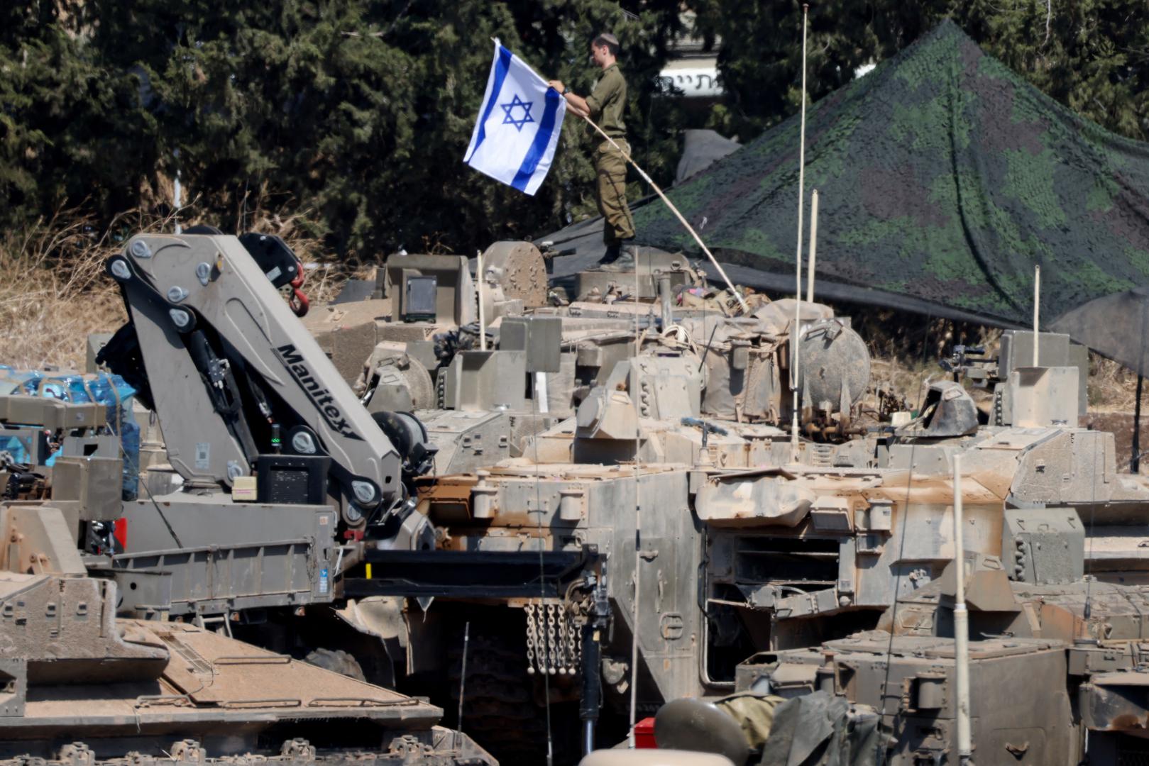 An Israeli member of the military adjusts an Israeli flag as armoured vehicles are arranged in formation, amid cross-border hostilities between Hezbollah and Israel, in northern Israel, September 30, 2024. REUTERS/Jim Urquhart Photo: JIM URQUHART/REUTERS