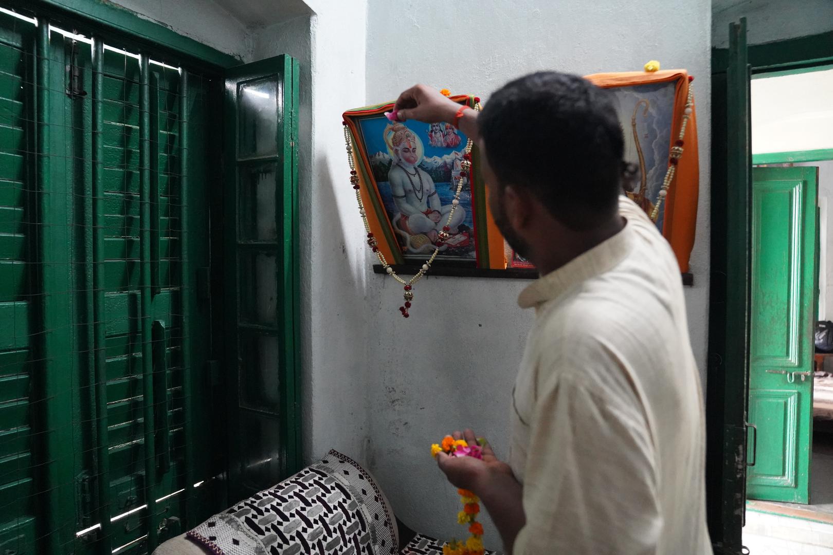 19 July 2024, India, Varanasi: The Hindu priest Kalikant Dubey decorates an image of God Hanuman in the Mukti Bhawan (House of Salvation). Photo: Anne-Sophie Galli/dpa Photo: Anne-Sophie Galli/DPA