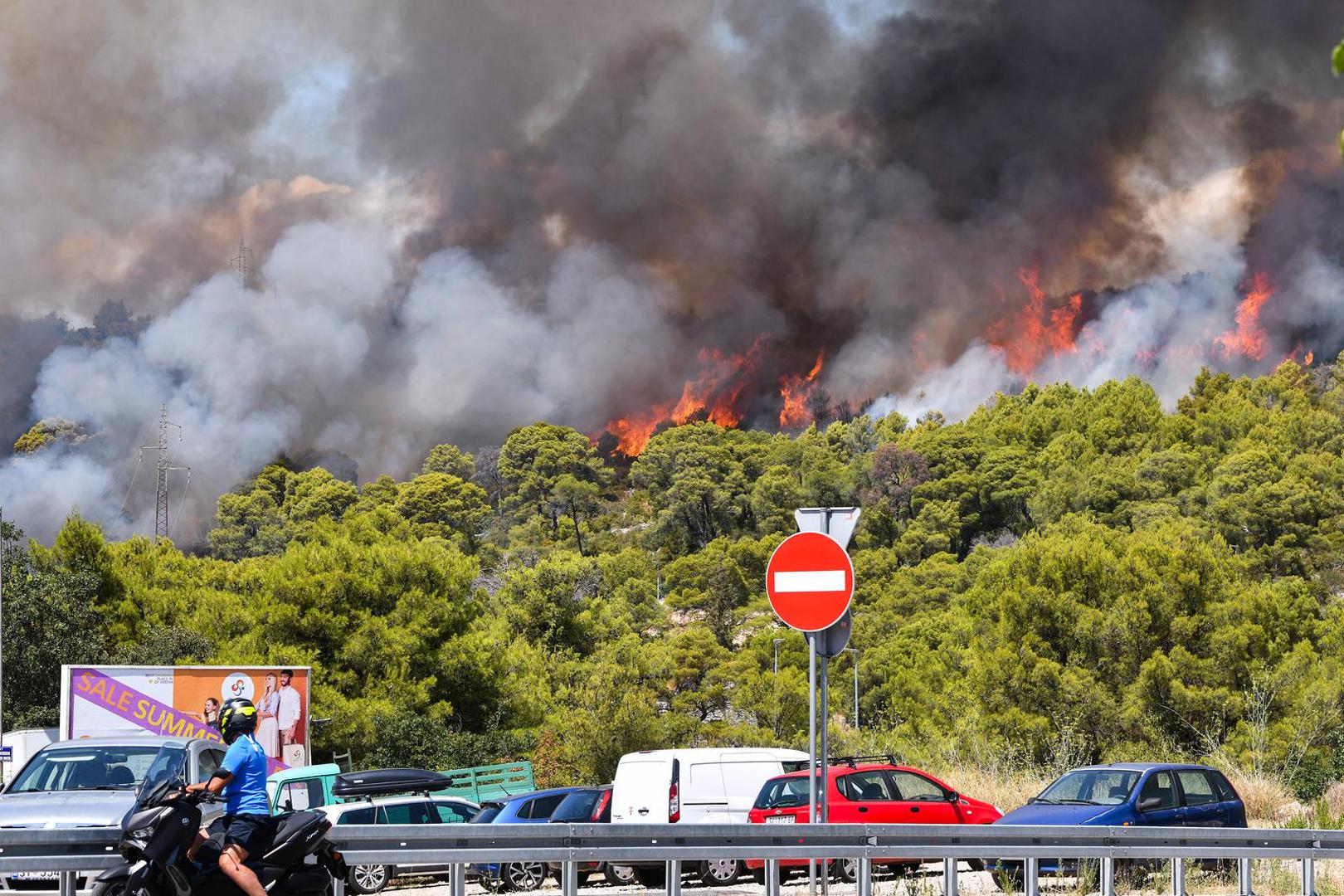 06.08.2024., Sibenik - Nesto prije 13 sati izbio je pozar u borovoj sumi u sibenskom naselju Rokici, odmah pokraj bolnice i stambenih kuca. Na terenu su vatrogasci i policija, a pozvana je i pomoc iz zraka. Suma se nalazi iznad Jadranske magistrale koja je zbog pozara zatvorena za sav promet. Photo: Hrvoje Jelavic/PIXSELL