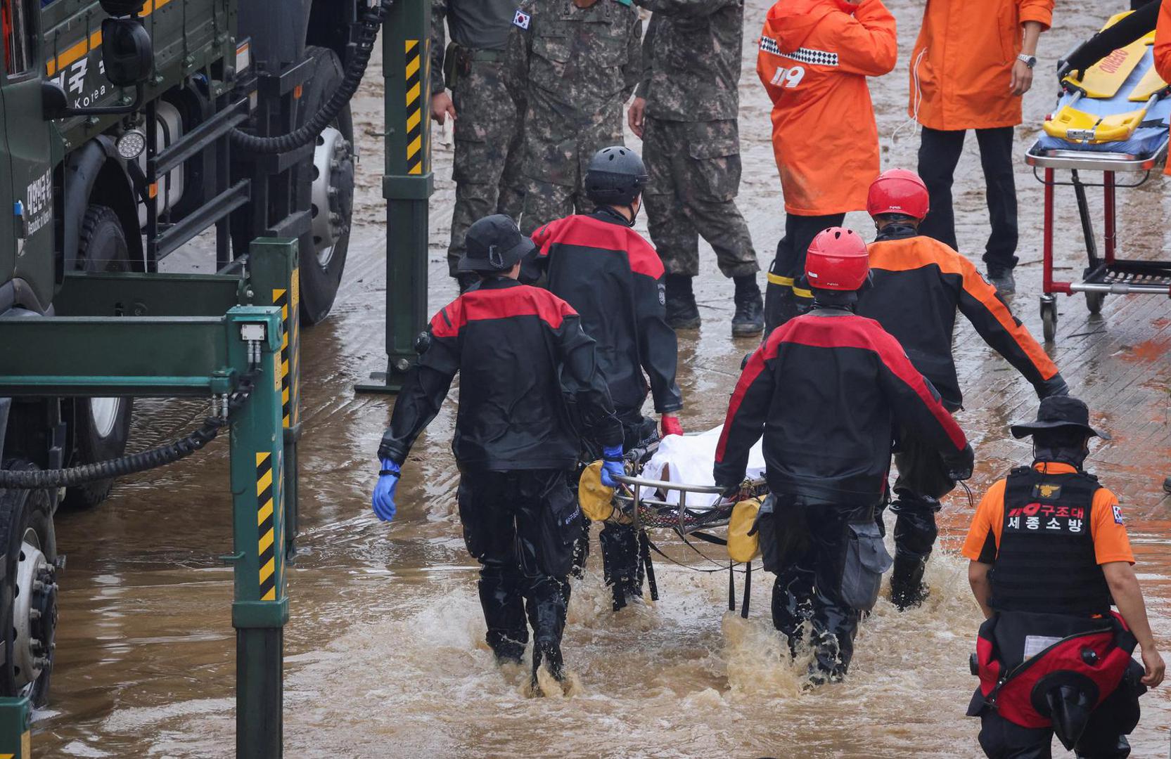 Rescue workers carry the body of a victim recovered during a search and rescue operation near an underpass that has been submerged by a flooded river caused by torrential rain in Cheongju, South Korea, July 16, 2023.   REUTERS/Kim Hong-ji Photo: KIM HONG-JI/REUTERS