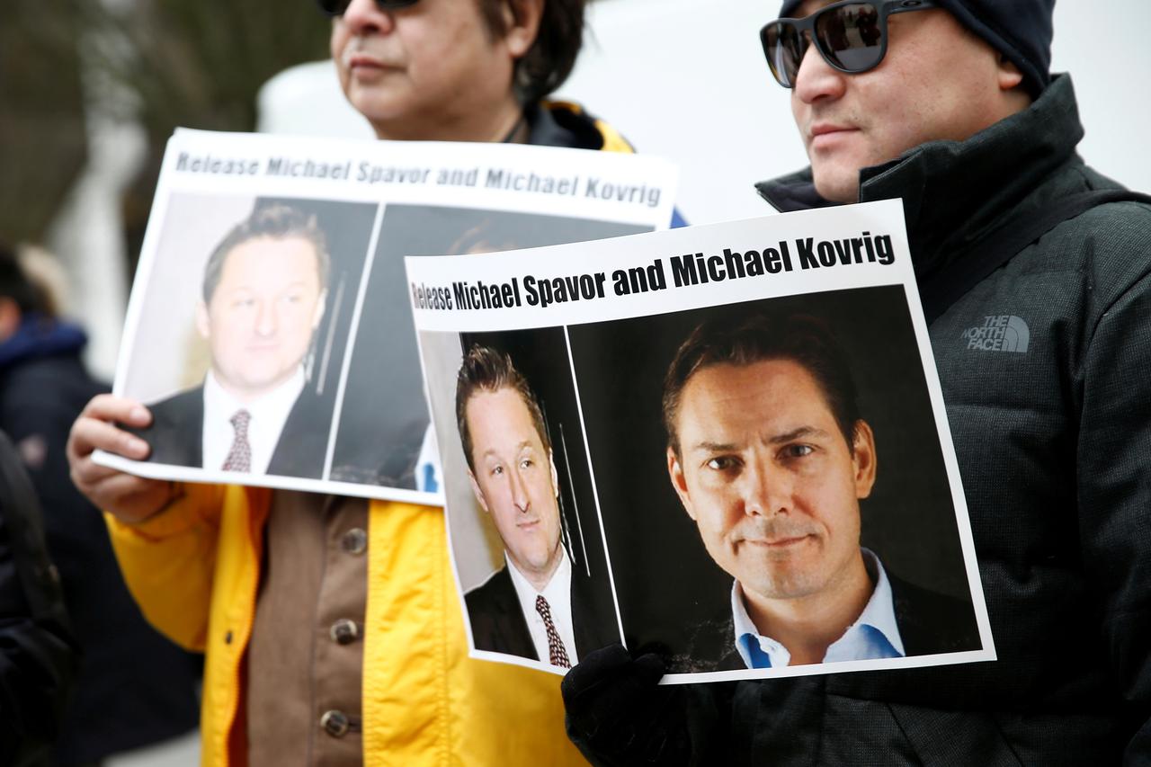 FILE PHOTO: People hold signs calling for China to release Canadian detainees Spavor and Kovrig during an extradition hearing for Huawei Technologies Chief Financial Officer Meng Wanzhou at the B.C. Supreme Court in Vancouver