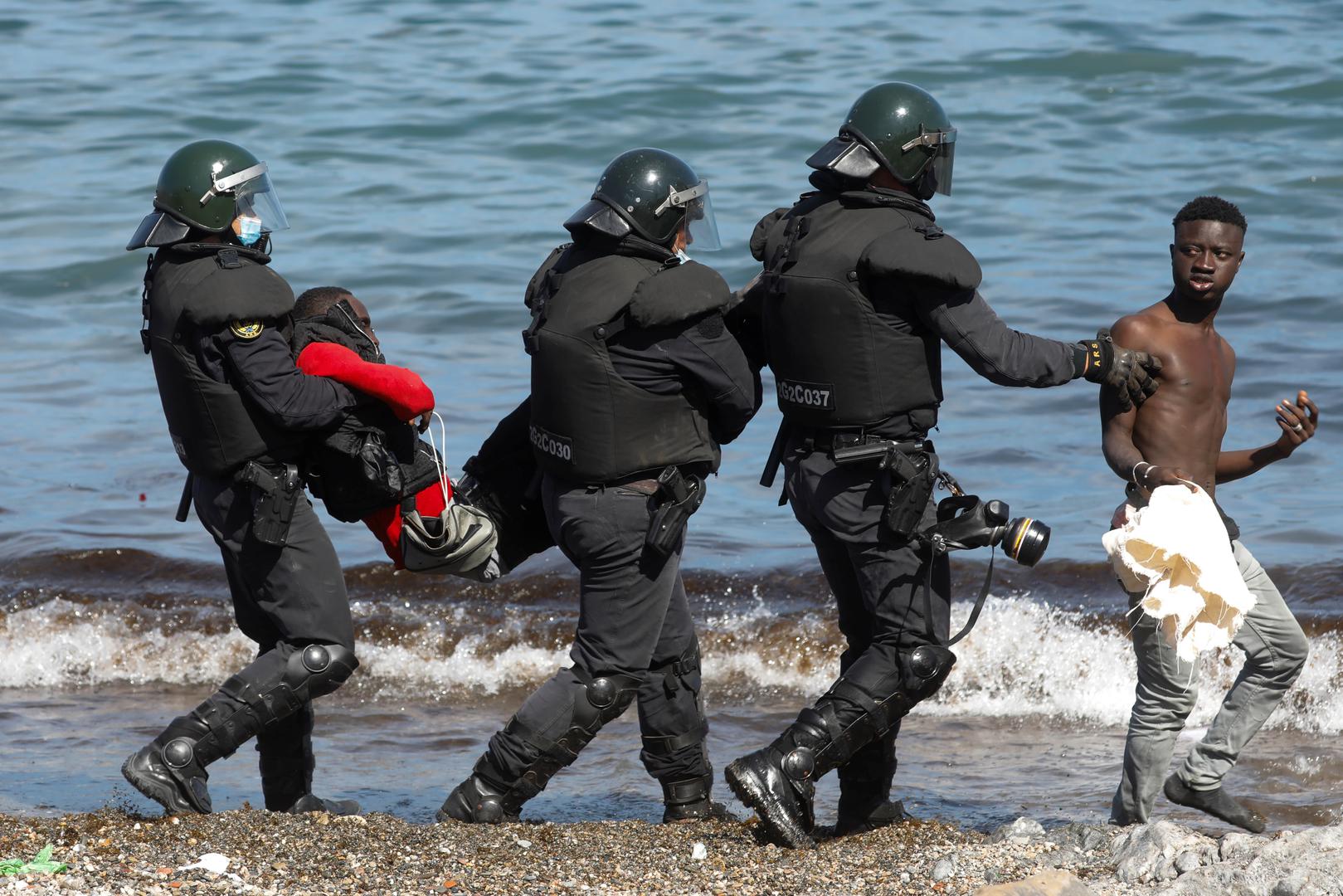 Thousands of migrants cross the Spanish-Moroccan border Spanish security forces members carry and escort Moroccan citizens at El Tarajal beach, near the fence between the Spanish-Moroccan border, after thousands of migrants swam across this border during last days, in Ceuta, Spain, May 18, 2021. REUTERS/Jon Nazca JON NAZCA