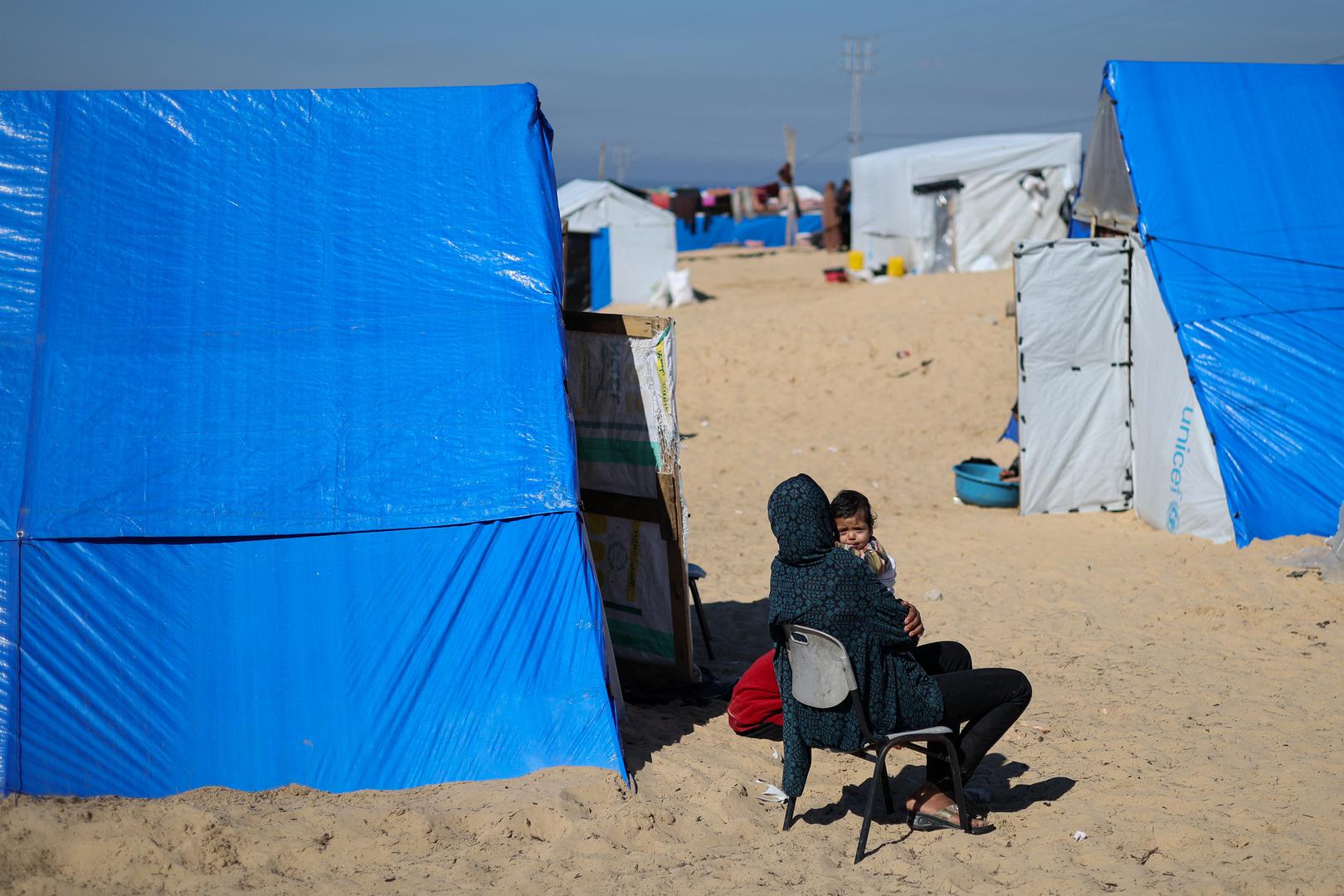 A woman sits with a baby next to tents as displaced Palestinians, who fled their houses due to Israeli strikes, take shelter in a tent camp, amid the ongoing conflict between Israel and the Palestinian Islamist group Hamas, at the border with Egypt, in Rafah in the southern Gaza Strip, February 8, 2024. REUTERS/Ibraheem Abu Mustafa Photo: IBRAHEEM ABU MUSTAFA/REUTERS