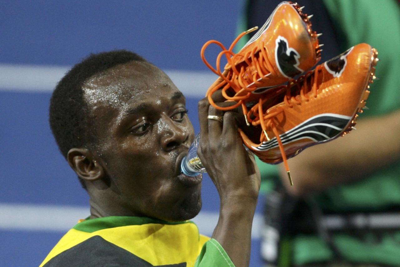 'Usain Bolt of Jamaica holds his shoes in his had as he celebrates winning the men\'s 200 metres during the world athletics championships at the Olympic stadium in Berlin August 20, 2009. Bolt won the