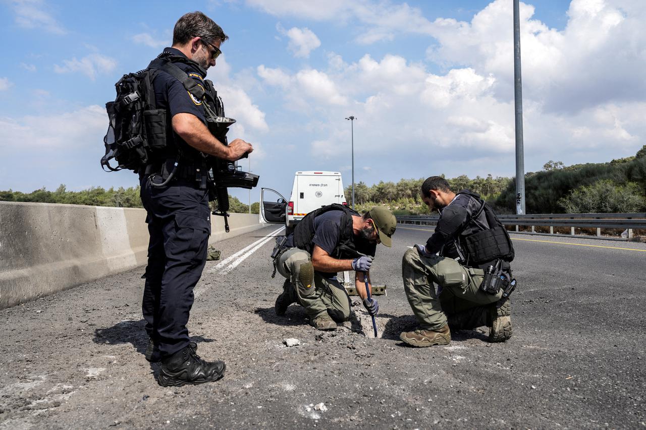 Police and explosive experts inspect the site where a rocket landed after it was fired from Lebanon into Israel, in northern Israel