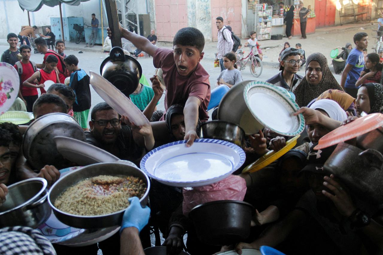 FILE PHOTO: Palestinian children gather to receive food cooked by a charity kitchen, amid food scarcity, as Israel-Hamas conflict continues, in the northern Gaza Strip