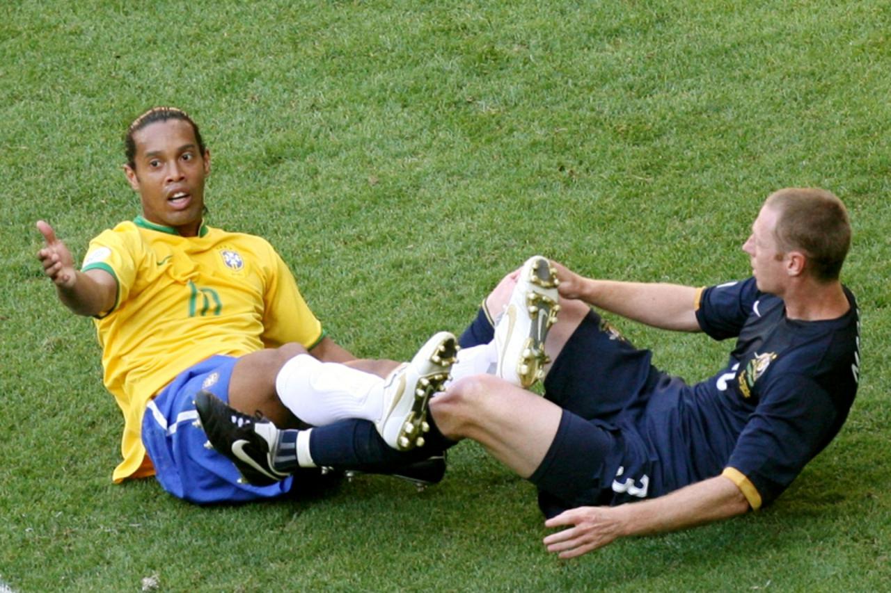 'Brazil\'s Ronaldinho (L) reacts after a tussle with Australia\'s Craig Moore during their Group F World Cup 2006 soccer match in Munich June 18, 2006.  FIFA RESTRICTION - NO MOBILE USE   REUTERS/Tom 