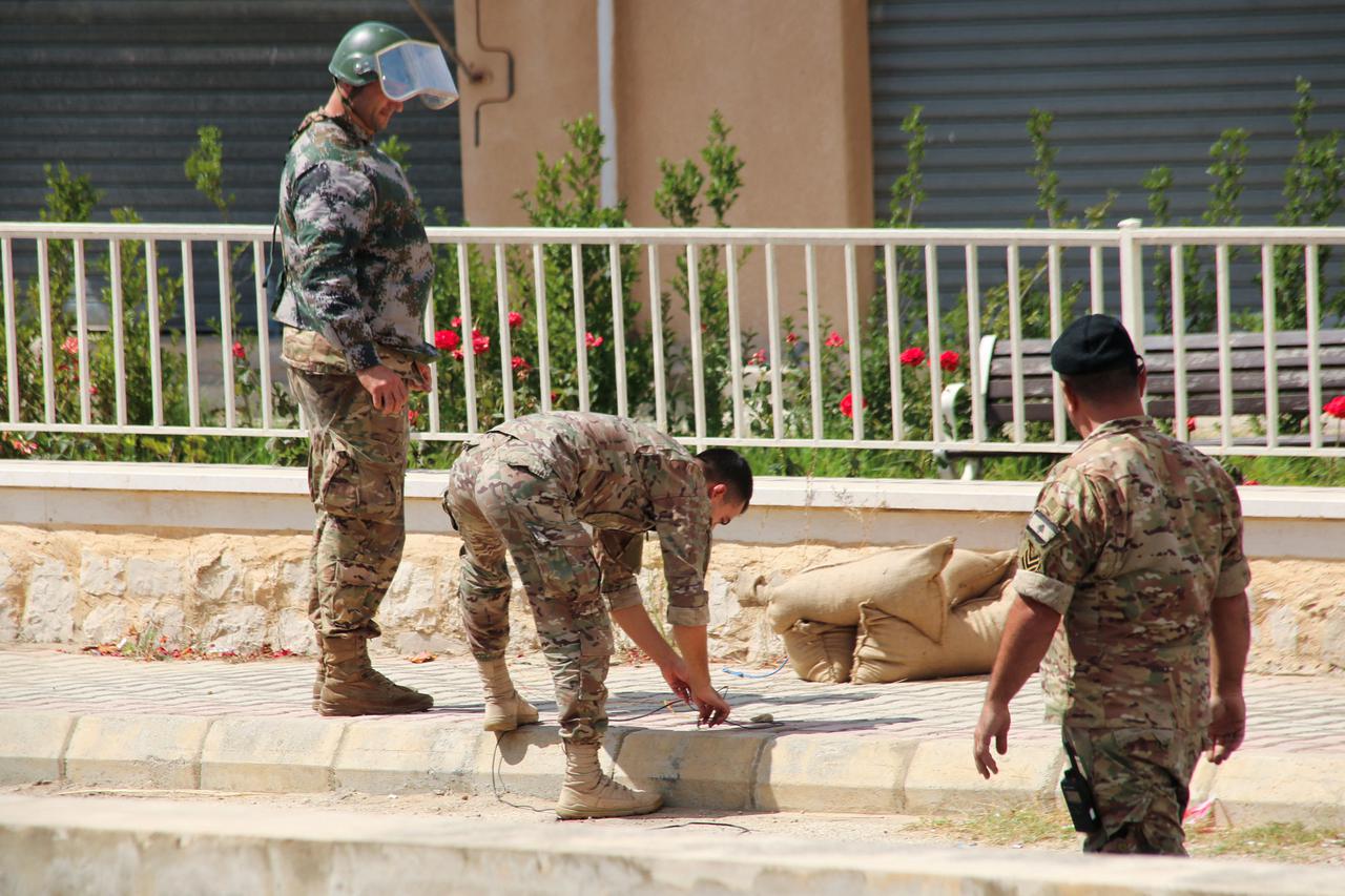 Lebanese army members prepare to carry out a controlled explosion of a battery of a communications device in the town of Qlayaa