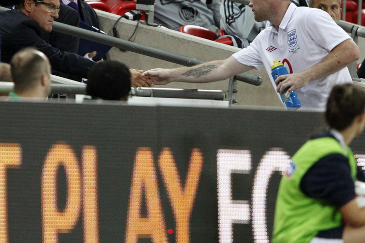 'England\'s coach Fabio Capello (L) shakes hands with Wayne Rooney after substituting him during their international friendly soccer match against Hungary at Wembley Stadium in London August 11, 2010.