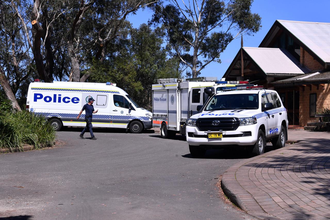 Police personnel work near the site where a landslide killed two people west of Sydney