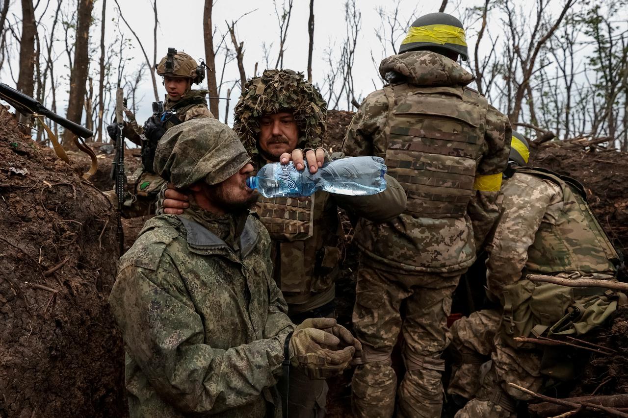 A Ukrainian soldier gives waterto a captured Russian army serviceman near the front line city of Bakhmut