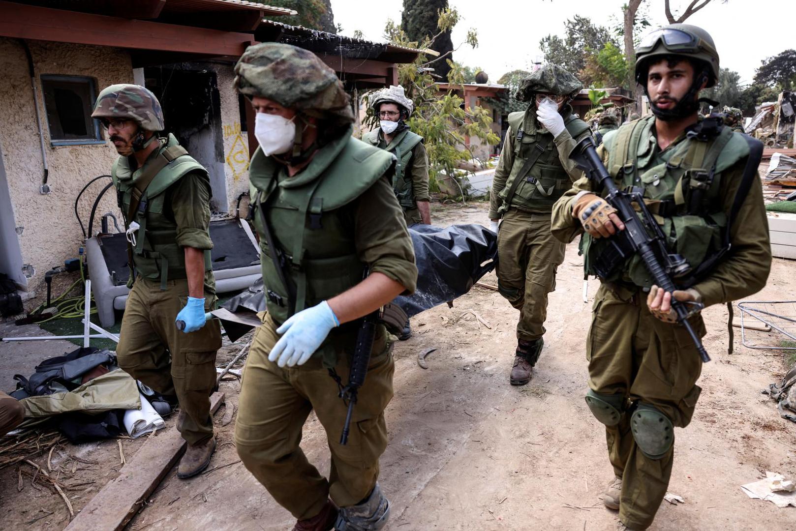 Israeli soldiers carry a dead body as they collect bodies following attacks from Gaza at Kibbutz Kfar Aza, in southern Israel, October 10, 2023. REUTERS/Ronen Zvulun Photo: RONEN ZVULUN/REUTERS