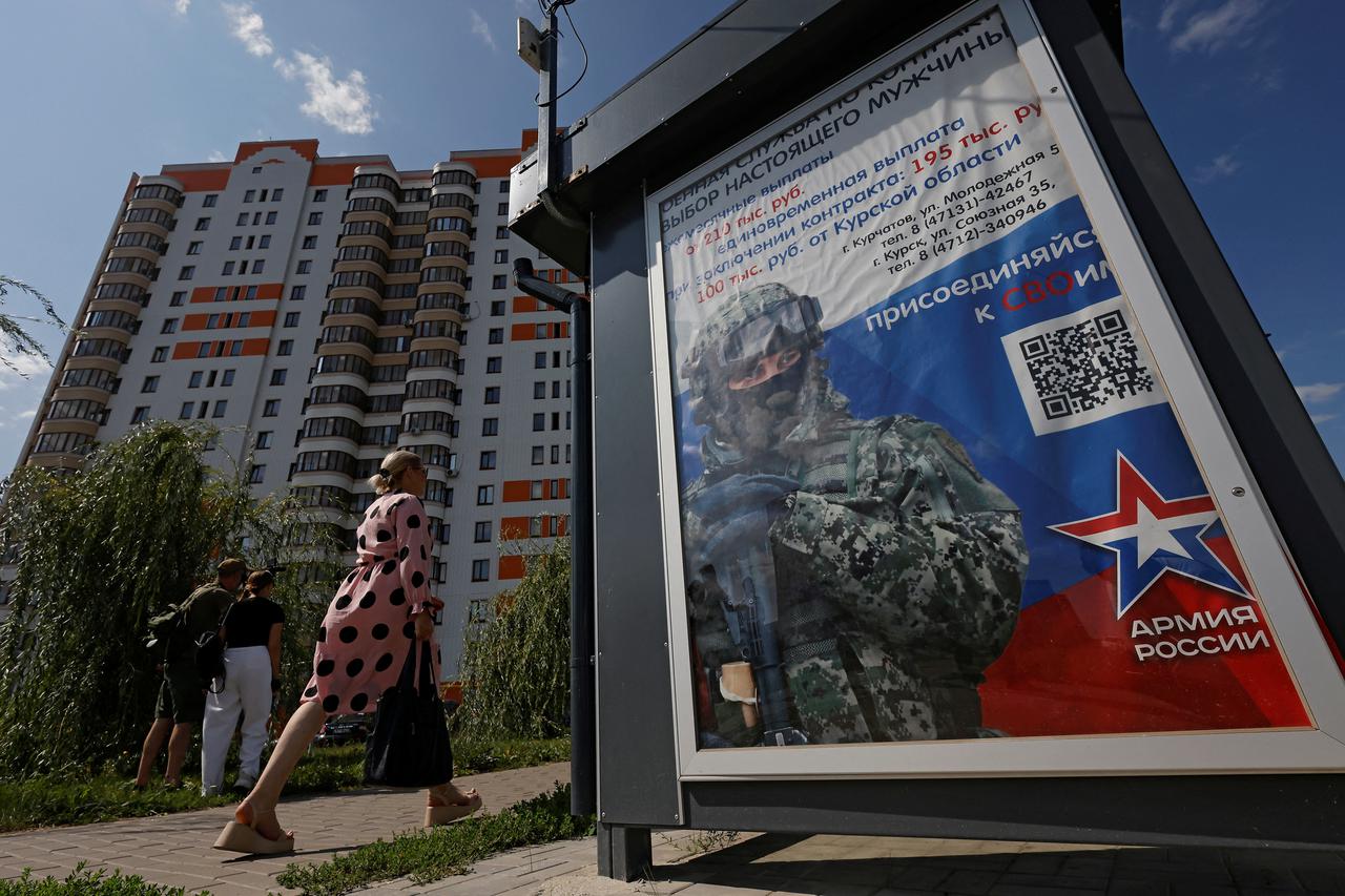 A woman walks past a poster promoting military service in Kurchatov