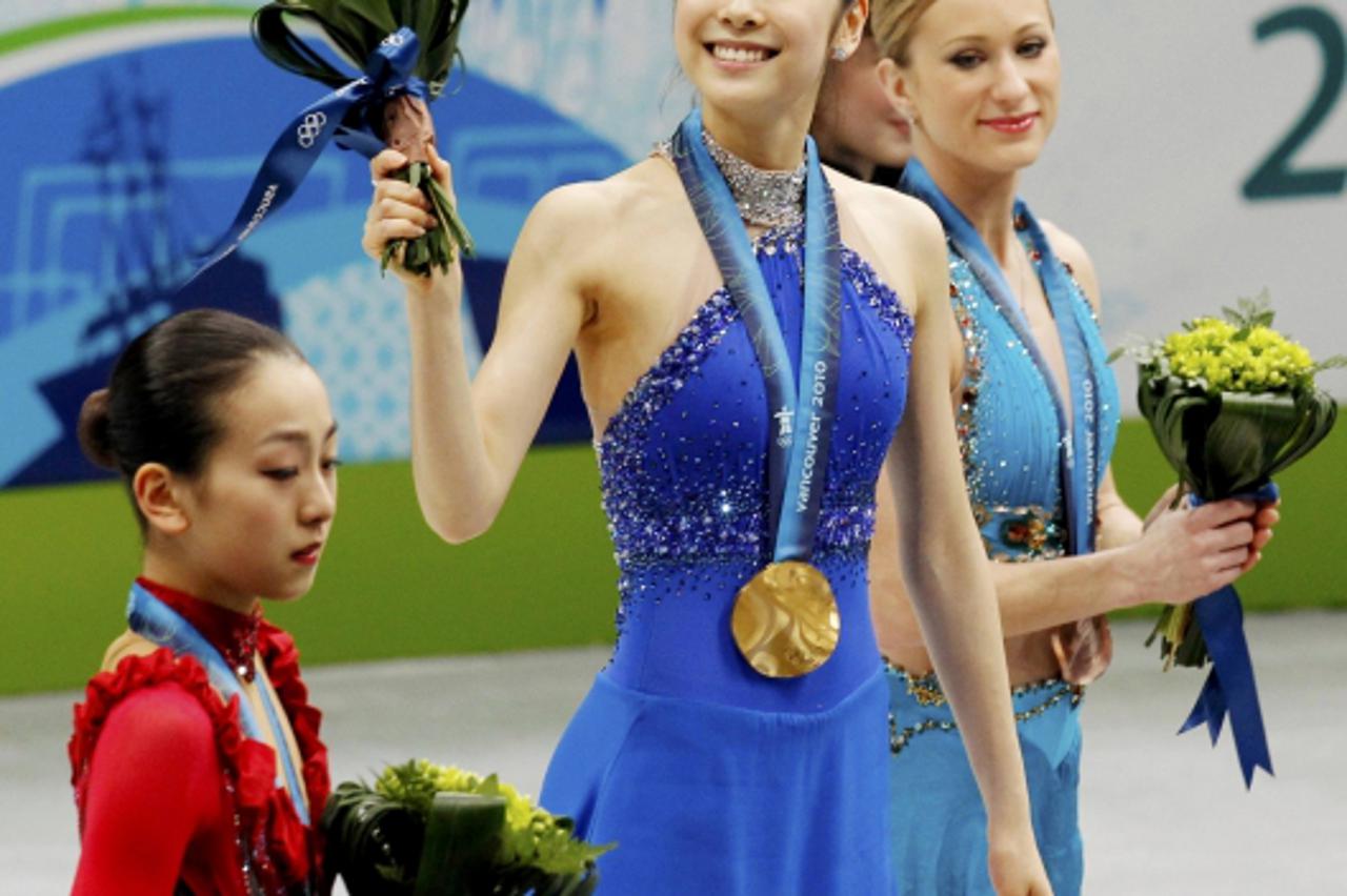 'Gold medallist South Korea\'s Kim Yu-Na (C) smiles on the podium alongside silver medallist Japan\'s Mao Asada (L) and bronze medallist Canada\'s Joannie Rochette during the victory ceremony for the 