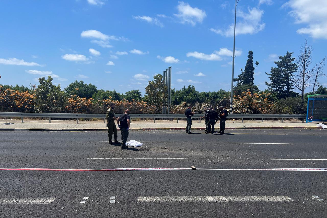 An Israeli policeman and soldier inspect the impact site of a projectile, after Lebanon's armed group Hezbollah said it launched a swarm of attack drones against military targets in northern Israel, in Nahariya