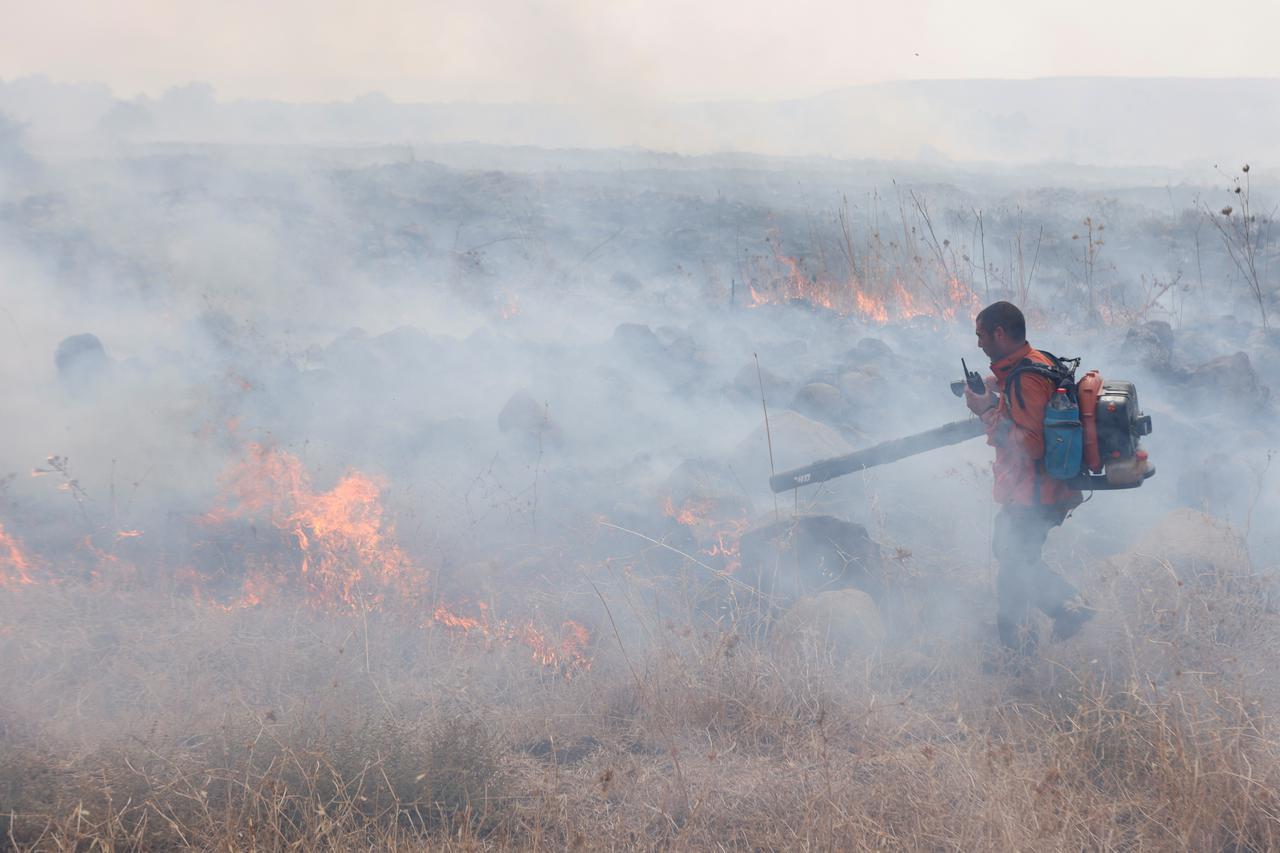 A man attempts to extinguish flames following a rocket attack from Lebanon, in the Israeli-occupied Golan Heights