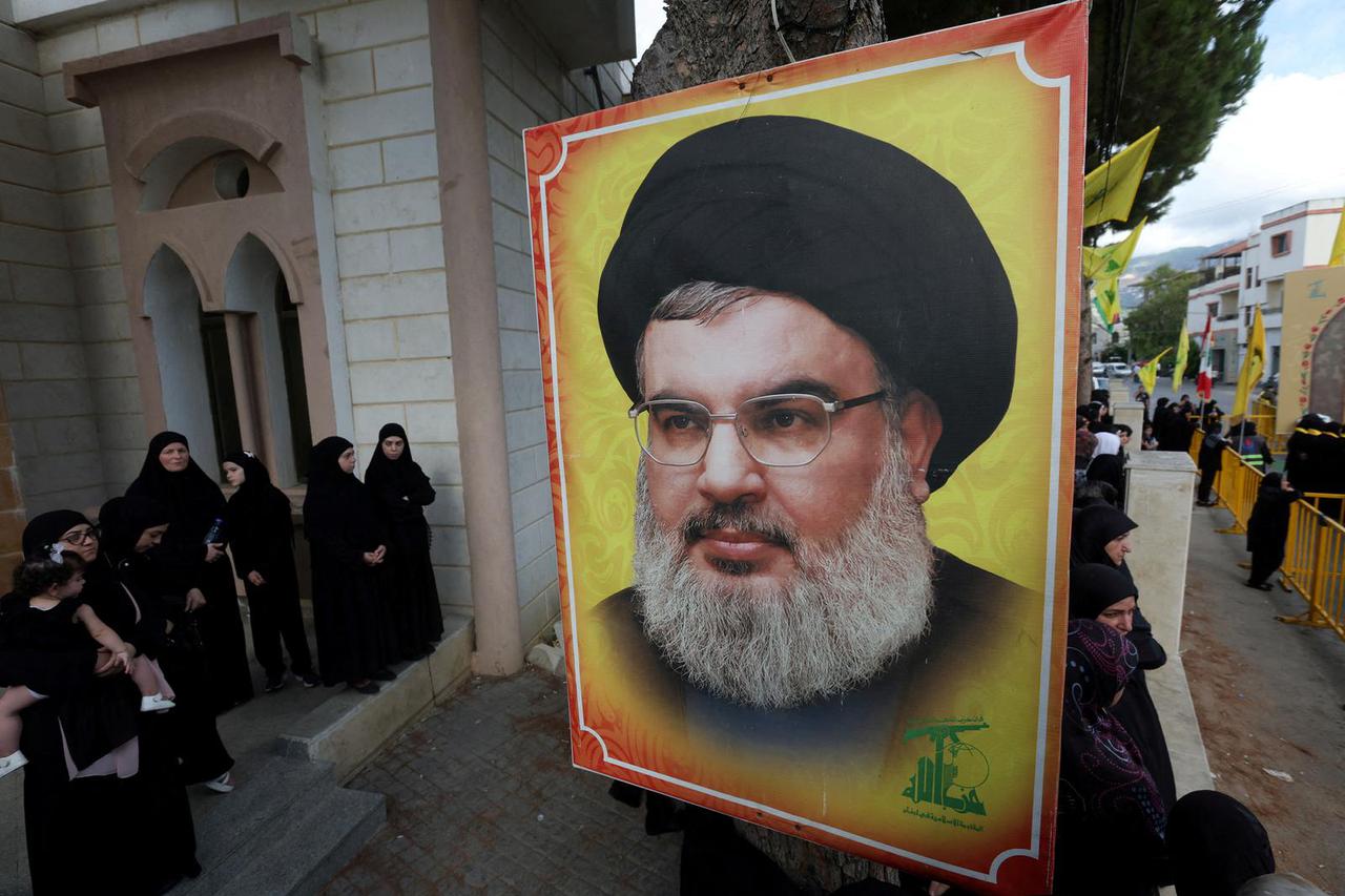 FILE PHOTO: People stand near a picture of Hezbollah leader Sayyed Hassan Nasrallah in Kfar Melki