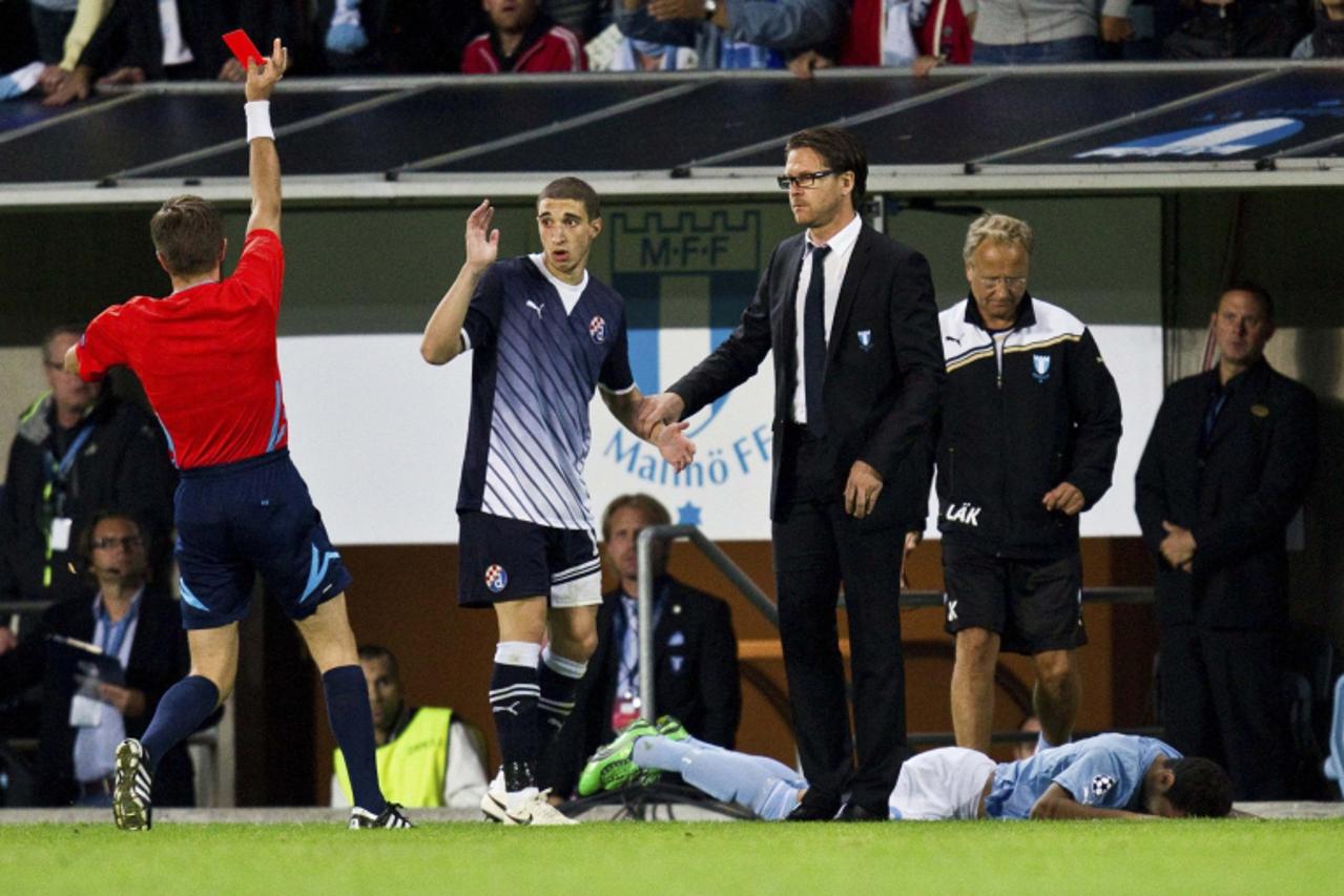 'Referee Nicola Rizzoli (L) shows Dynamo Zagreb\'s Sime Vrsaljko (C) the red card next to Malmo coach Rikard Norling (R) during their Champions League play-off 2nd leg soccer match at Malmo new stadiu