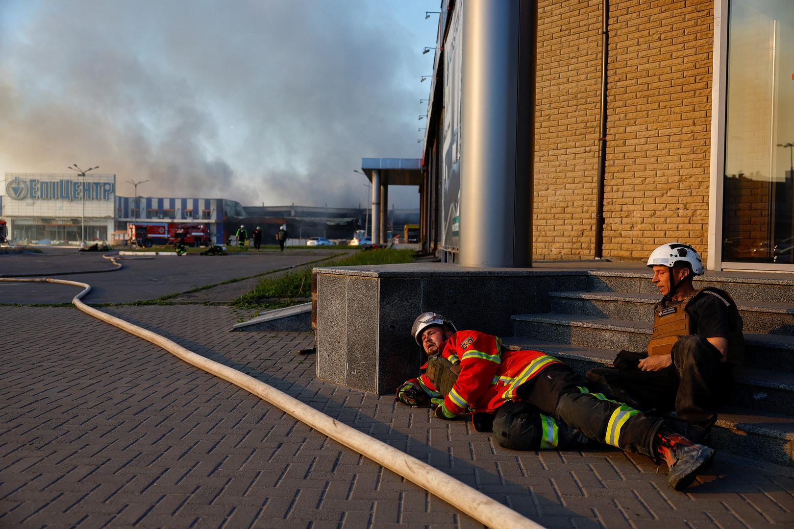 First responders take cover, after the announcement of a Russian missile attack towards Kharkiv, as smoke rises from the site of a household item shopping mall which was hit by a Russian air strike, amid Russia's attack on Ukraine, in Kharkiv, Ukraine, May 25, 2024. REUTERS/Valentyn Ogirenko Photo: VALENTYN OGIRENKO/REUTERS