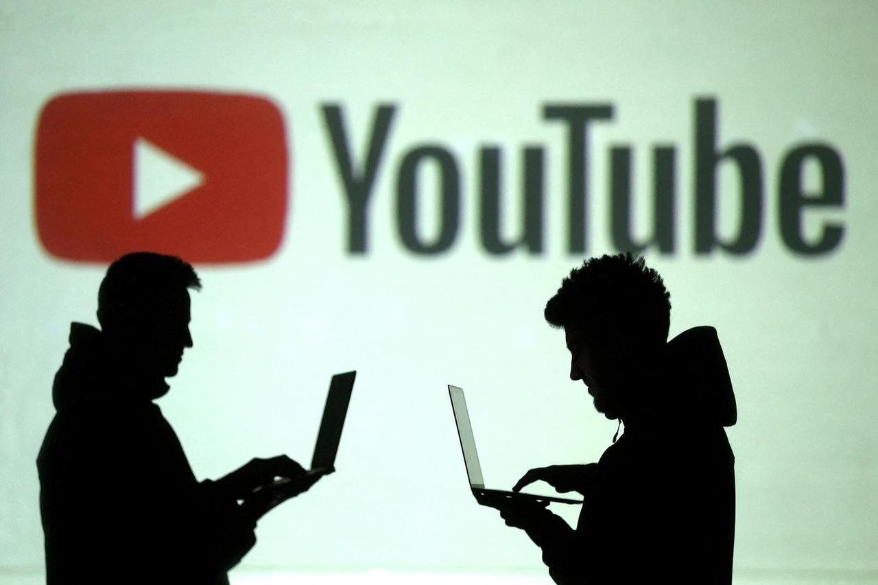 FILE PHOTO: Silhouettes of mobile device users are seen next to a screen projection of Youtube logo in this picture illustration