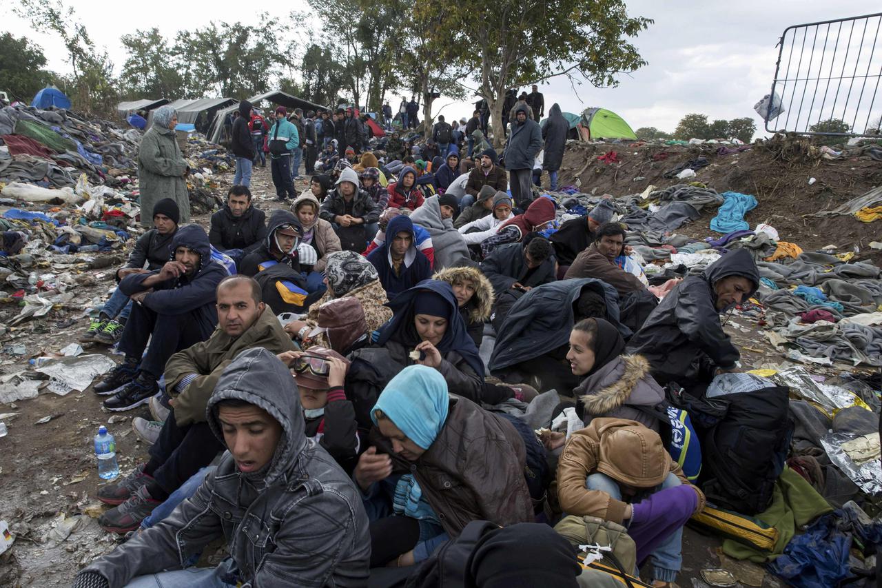 Migrants sit along a road as they wait to cross the border with Croatia near the village of Berkasovo, Serbia October 21, 2015. About 3,500 migrants spent the night camped out in freezing cold at the Berkasovo-Bapska border crossing between Serbia and Cro