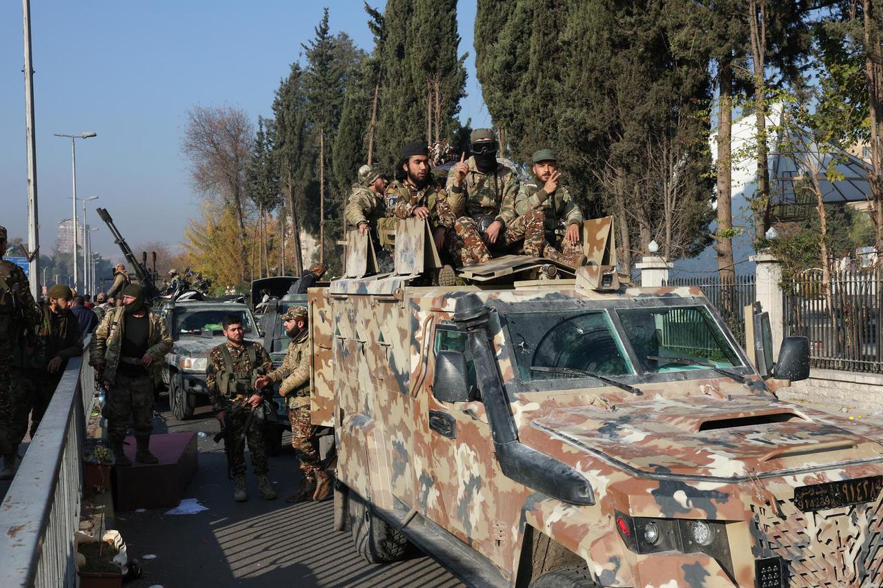 Rebel fighters sit on a vehicle, in Damascus