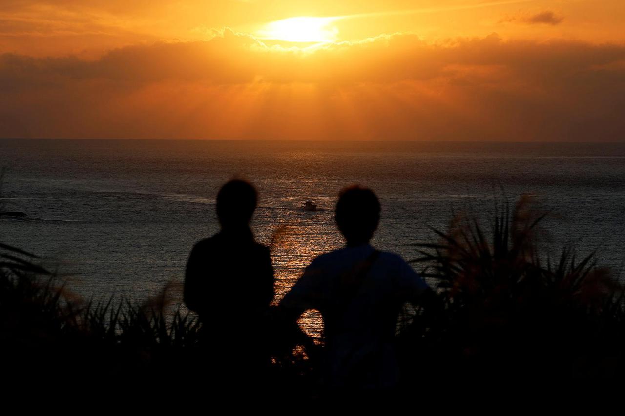 Visitors watch the sunset on the East China Sea at an observation point where Taiwanese mountains are visible a few times a year on Yonaguni island, Okinawa