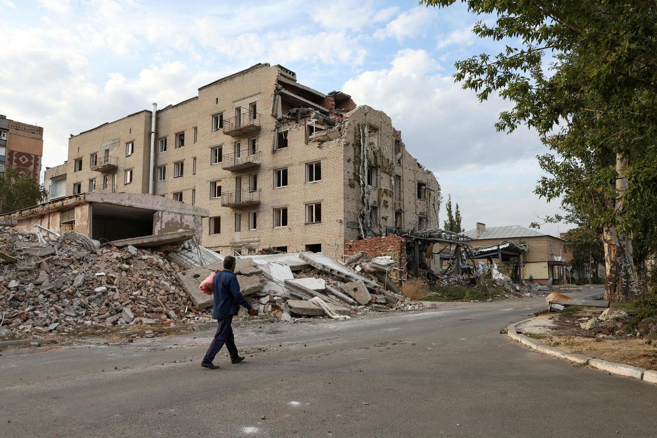 FILE PHOTO: Man walks past a building damaged by a Russian military strike in seen in the town of Pokrovsk