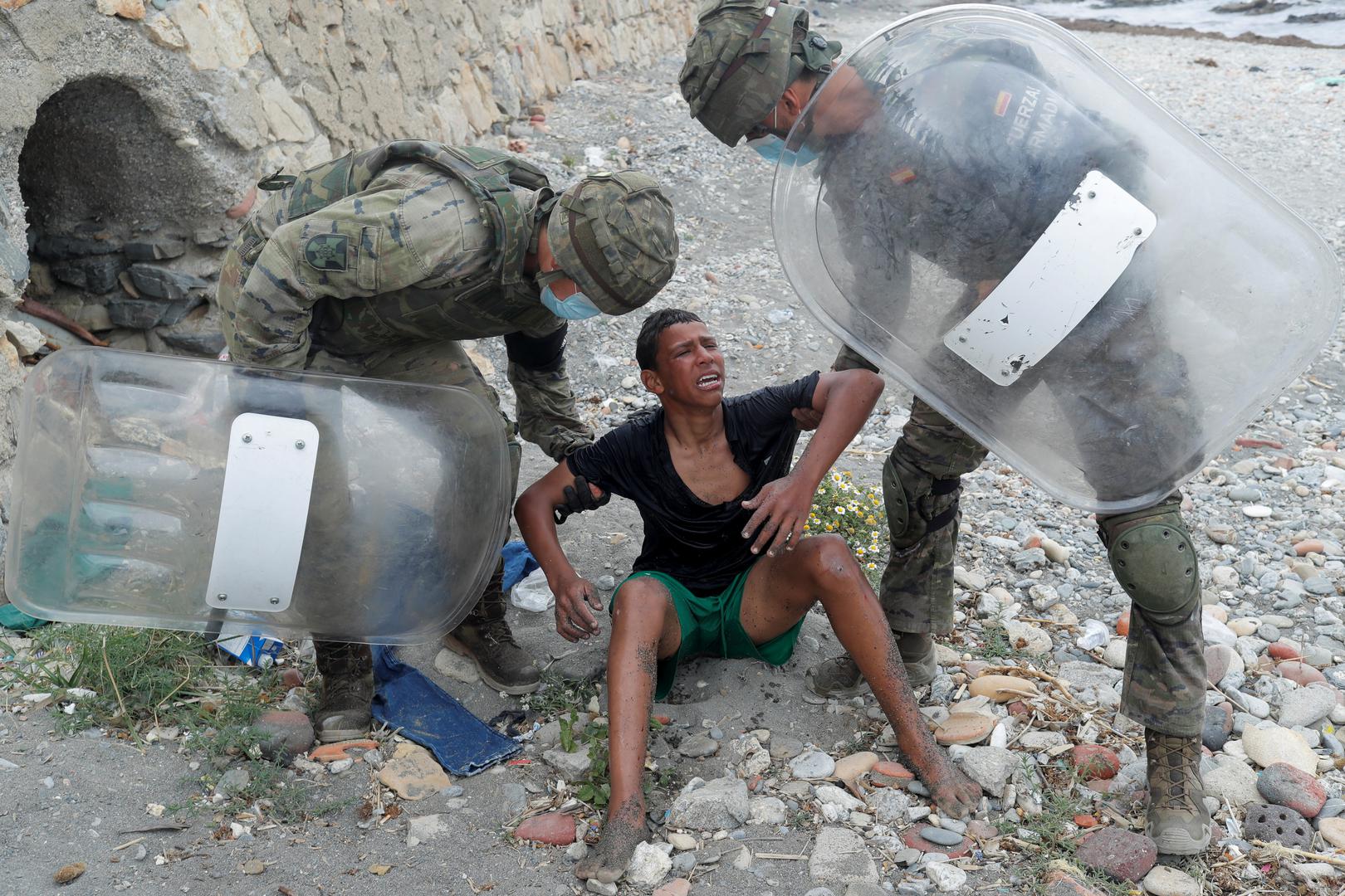 Thousands of migrants cross the Spanish-Moroccan border A Moroccan boy cries as he is helped by Spanish soldiers after he swam using bottles as a float, at El Tarajal beach, near the fence between the Spanish-Moroccan border, after thousands of migrants swam across the border, in Ceuta, Spain, May 19, 2021. REUTERS/Jon Nazca JON NAZCA