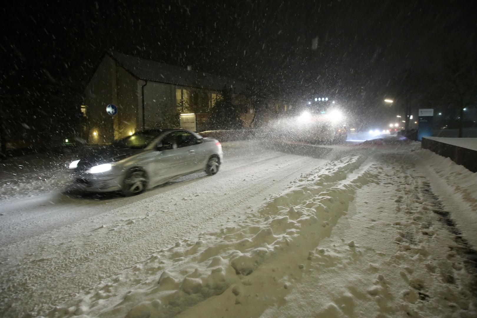 09 February 2021, Schleswig-Holstein, Malente: A car drives in front of a winter service vehicle on a road covered with snow in the village of Malente in the Ostholstein district. Photo: Bodo Marks/dpa /DPA/PIXSELL