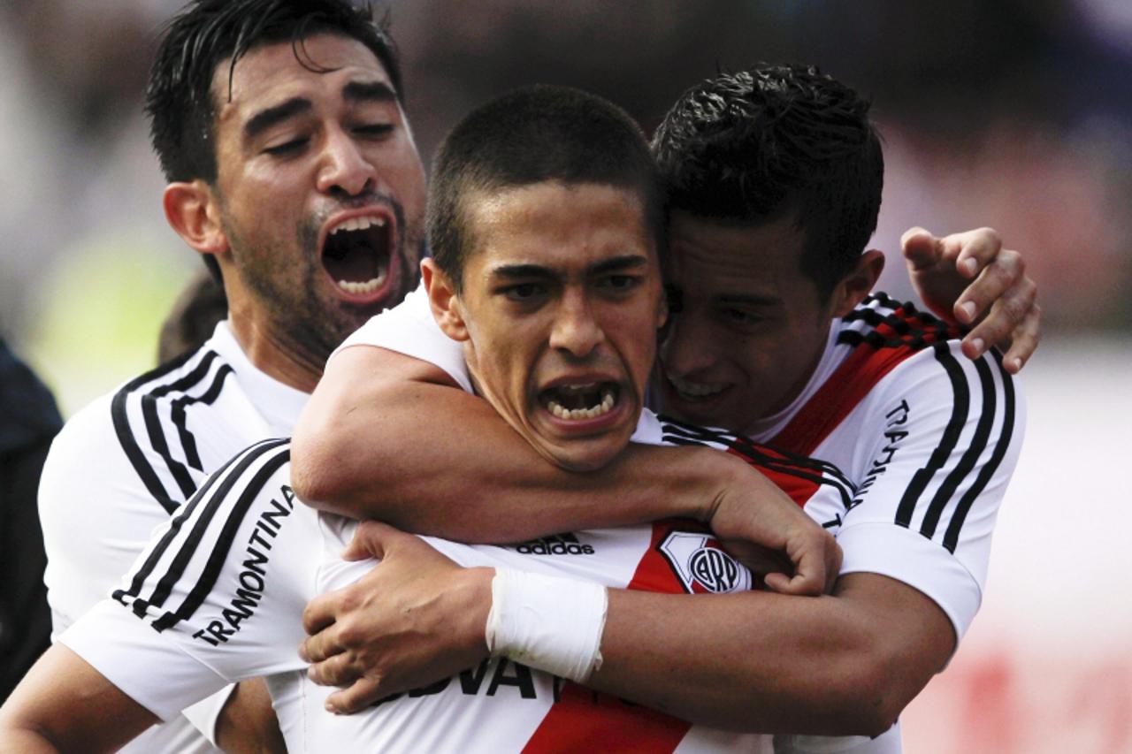 'River Plate\'s Manuel Lanzini (C) is embraced by teammates Rogelio Funes Mori (R) and Ariel Rojas after he scored his team\'s second goal against Independiente in their Argentine First Division socce