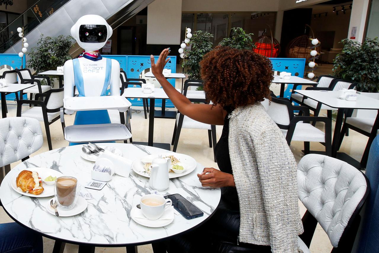 Caroline Nyaga reacts after the Robotic technology server delivers her meal order at the Robot Cafe, the food hub featuring robots that serves customers in Nairobi