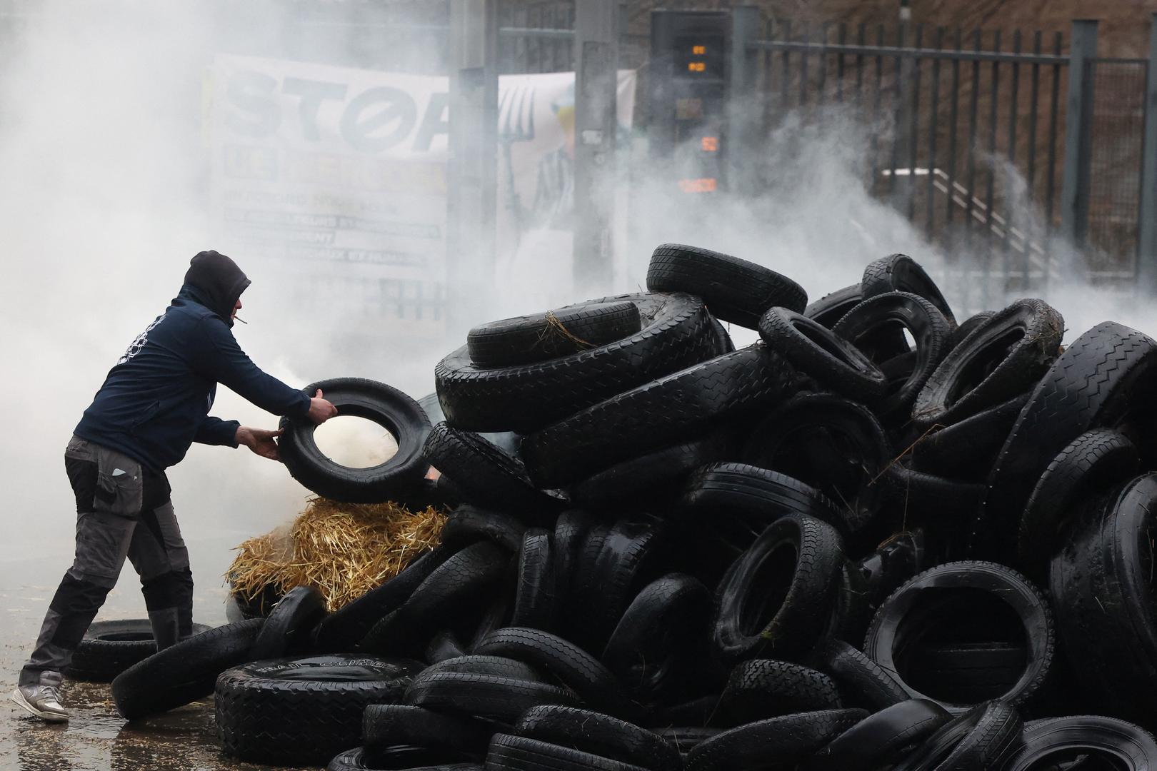 A man holds a tire as water is sprayed during a protest of European farmers over price pressures, taxes and green regulation, on the day of an EU Agriculture Ministers meeting in Brussels, Belgium February 26, 2024. REUTERS/Yves Herman Photo: YVES HERMAN/REUTERS