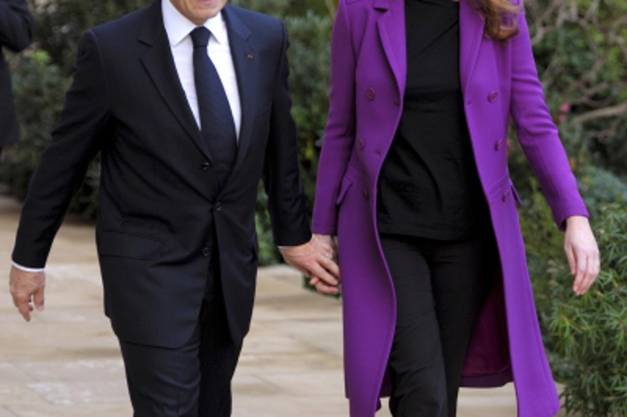 \'France\'s President Nicolas Sarkozy (L) and First Lady Carla Bruni-Sarkozy (R) walk to greet Ivory Coast First Lady Dominique Ouattara (not pictured) as she arrives at the Elysee Palace in Paris, on