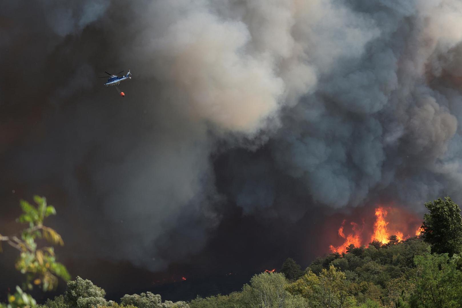 A helicopter flies near the smoke billowing from a wildfire burning at the border with Slovenia seen from Rupa, Italy, July 20, 2022. REUTERS/Borut Zivulovic Photo: BORUT ZIVULOVIC/REUTERS