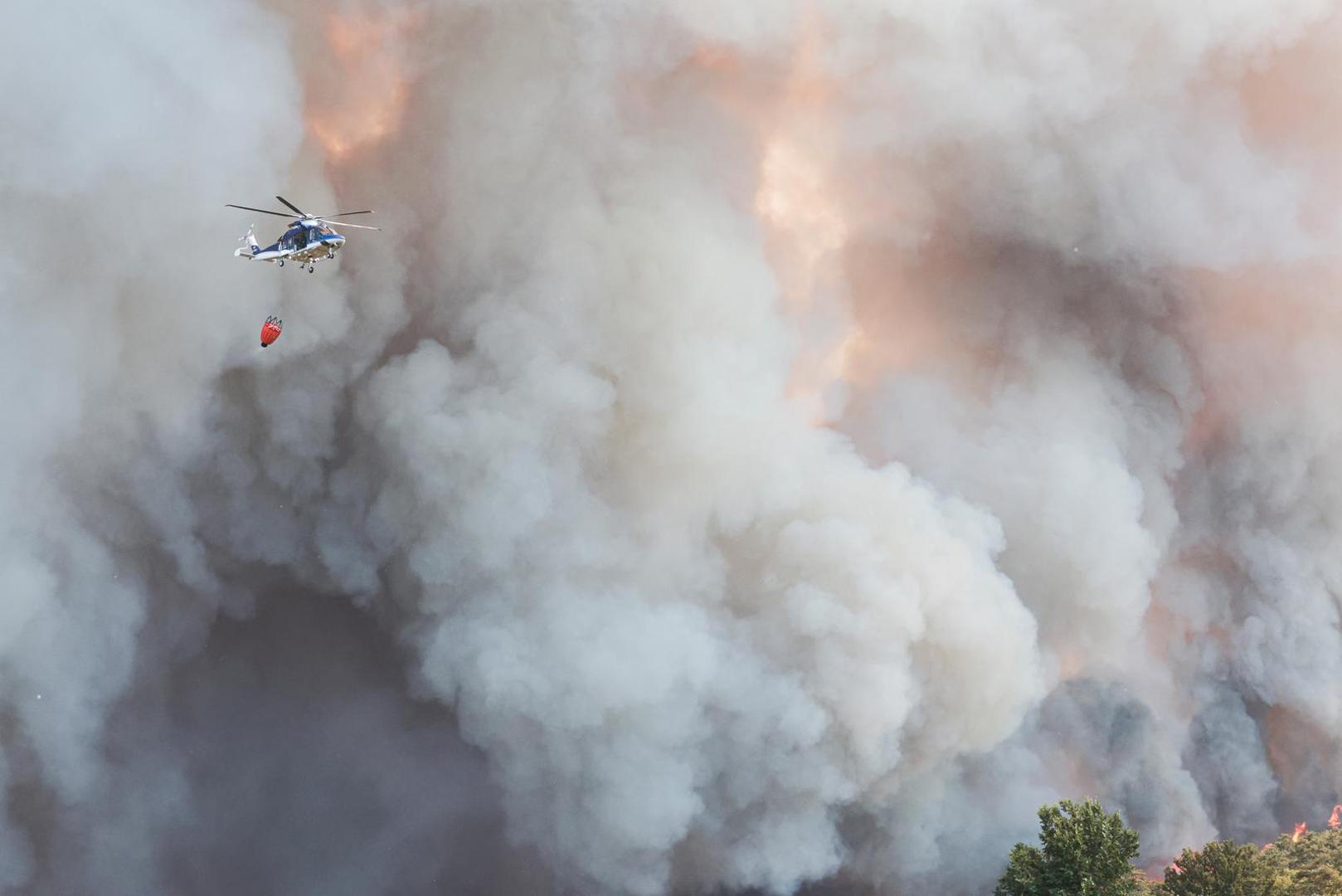 A helicopter flies near the smoke billowing from a wildfire at the border with Slovenia seen from Rupa, Italy, July 20, 2022. REUTERS/Borut Zivulovic Photo: BORUT ZIVULOVIC/REUTERS