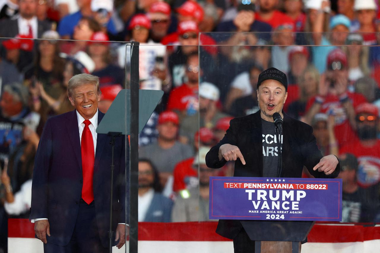 FILE PHOTO: Tesla CEO and X owner Elon Musk speaks as Republican presidential nominee and former U.S. president Donald Trump reacts during a rally in Butler