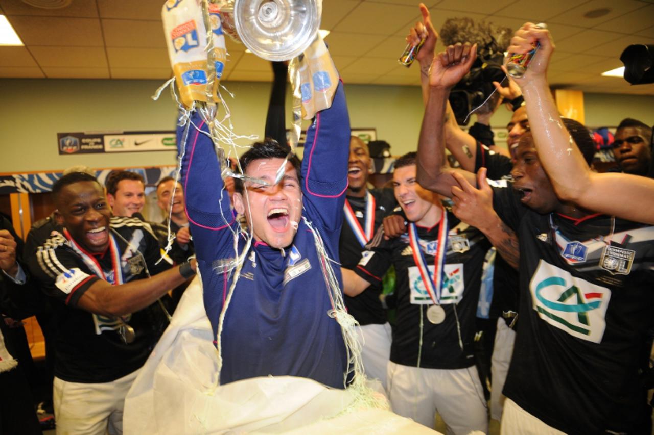 'Lyon\'s Croatian defender Dejan Lovren (C) holds the trophy flanked with his teammates in the locker room at the end of the French Cup final football match Olympique Lyonnais vs. US Quevilly, on Apri