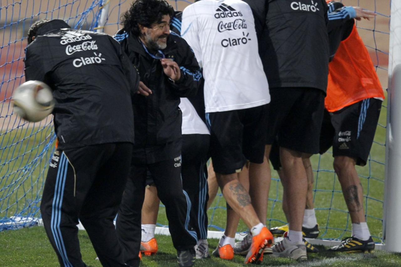 'Argentina\'s coach Diego Maradona, staff members and players shield from balls thrown at them by other players during a training soccer session in Pretoria, June 30, 2010.  REUTERS/Enrique Marcarian 