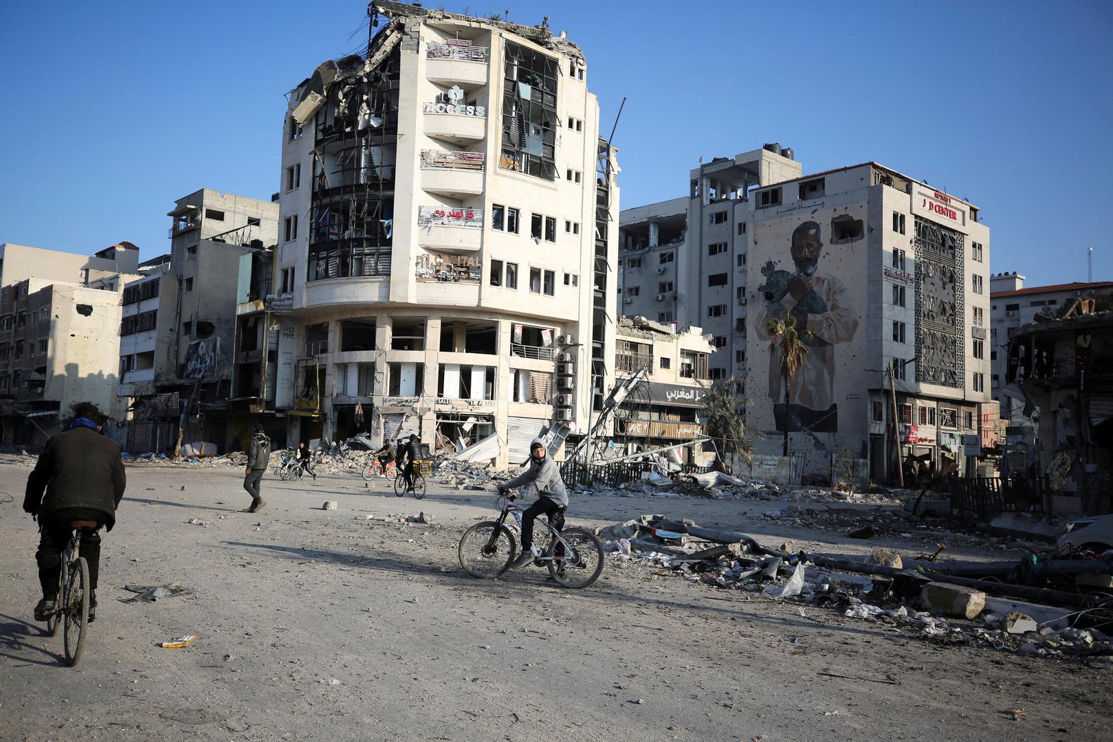 Palestinians ride bikes near damaged residential buildings following an Israeli ground operation, amid the ongoing conflict between Israel and Hamas, in Gaza City, February 10, 2024. REUTERS/Stringer Photo: Stringer/REUTERS