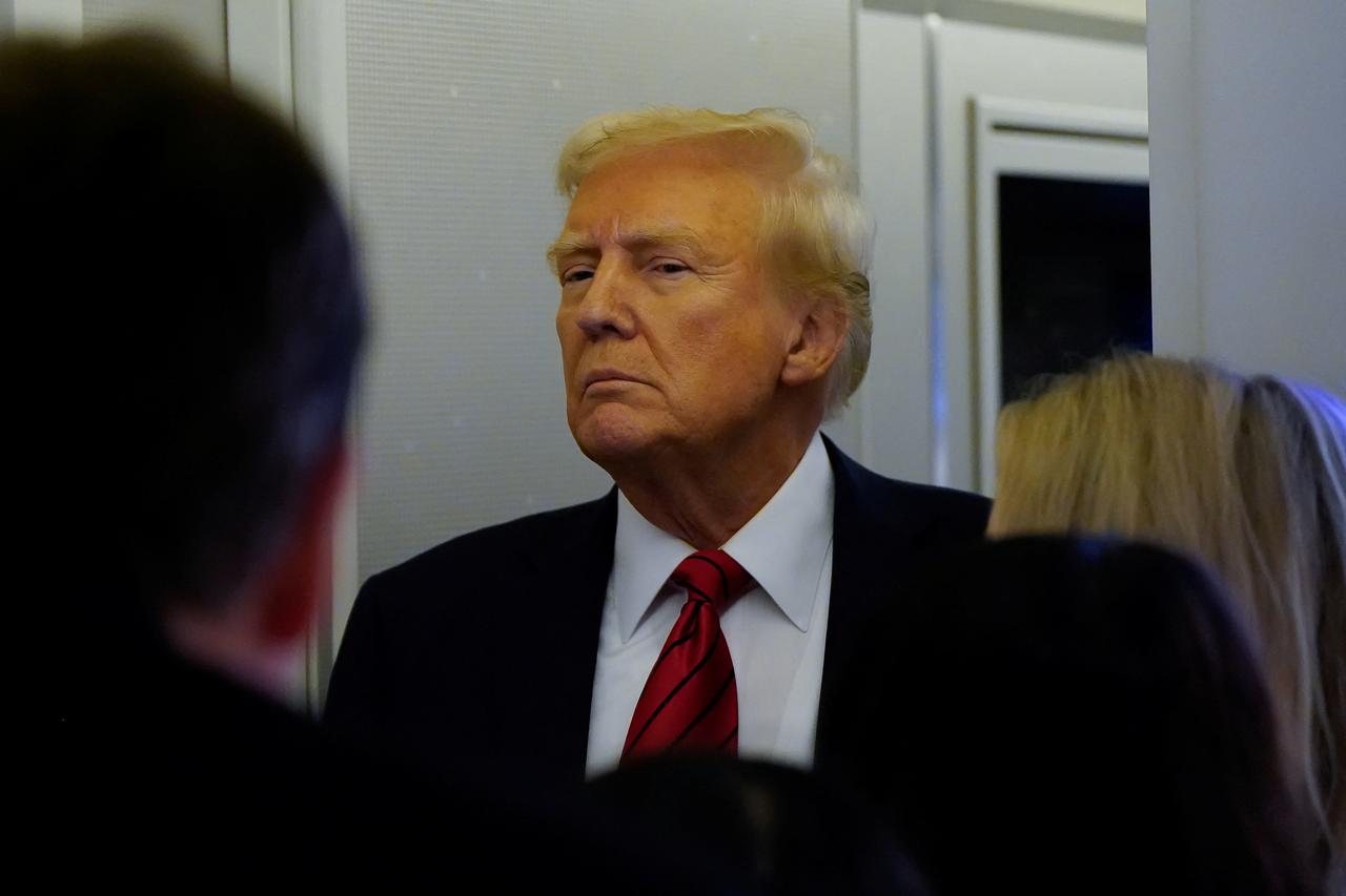 U.S. President Donald Trump speaks to reporters aboard Air Force One